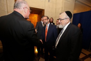 Leon Goldenberg, member of Agudath Israel of America's board of trustees warmly greets Cardinal Timothy Dolan in Albany as Rabbi Shmuel Lefkowitz, Agudath Israel's vice president for community affairs (R) and Yossi Menczer look on